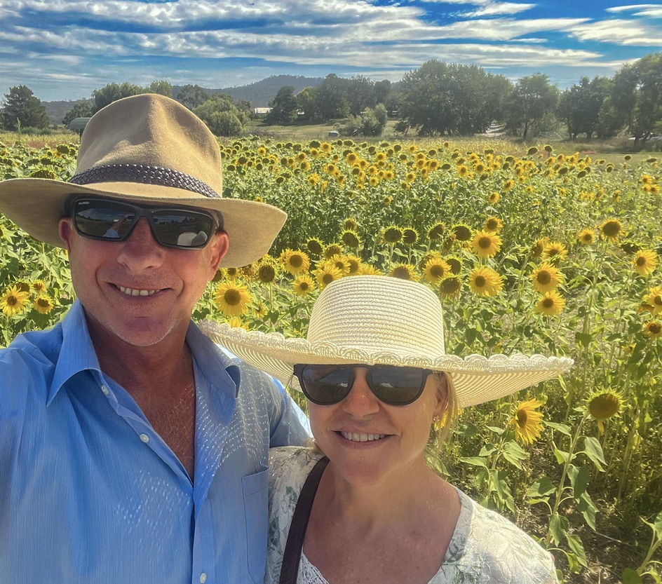 Will Collett and a woman in sun hats standing in front of a field of sunflowers